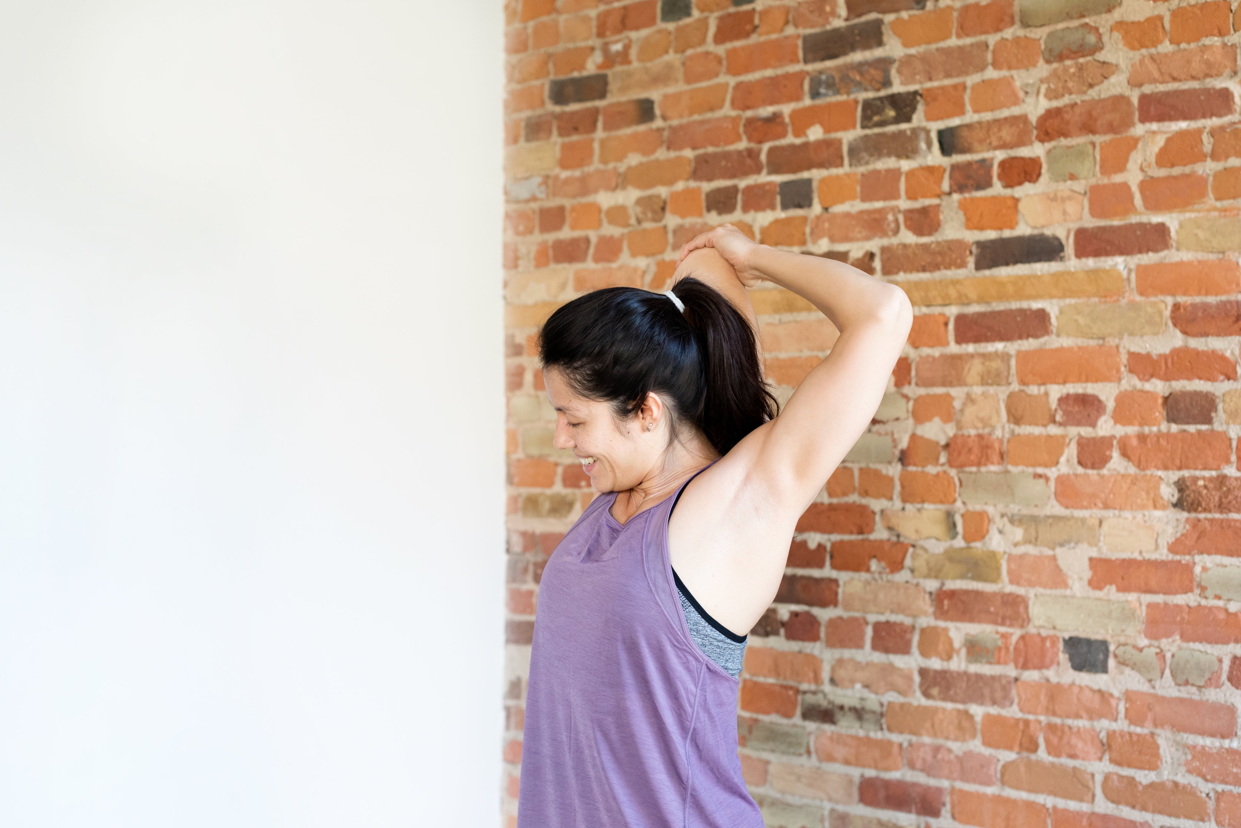 young-woman-exercising-in-workout-clothes-against-brick-wall.jpg